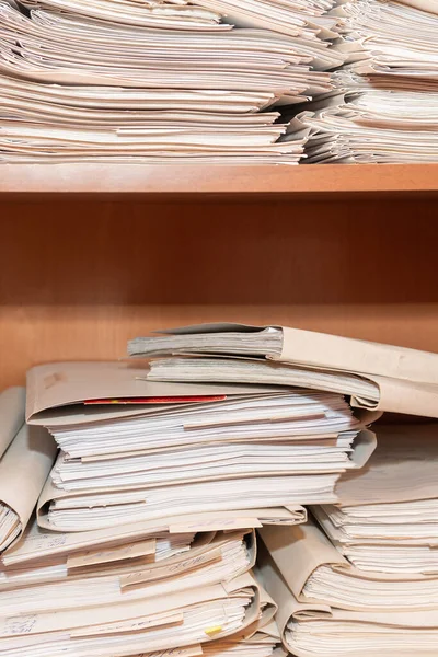 Old paper documents stacked in archive. Documents on the shelves of archive room. Office shelves in the closet full of files