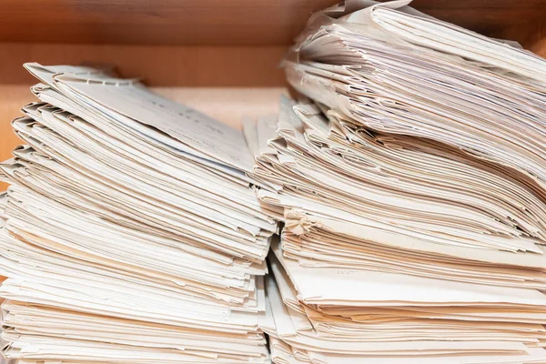 Old paper documents stacked in archive. Documents on the shelves of archive room. Office shelves in the closet full of files