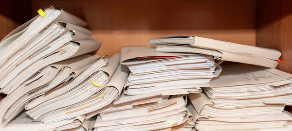 Old paper documents stacked in archive. Documents on the shelves of archive room. Office shelves in the closet full of files