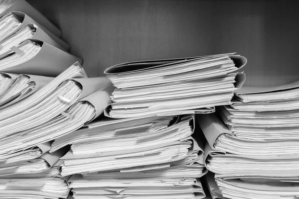 Paper documents stacked in archive. Documents on the shelves of archive room. Office shelves in the closet full of files. black and white photo