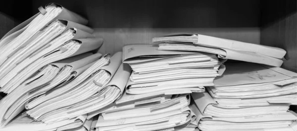 Paper documents stacked in archive. Documents on the shelves of archive room. Office shelves in the closet full of files. black and white photo