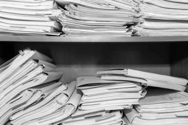 Paper documents stacked in archive. Documents on the shelves of archive room. Office shelves in the closet full of files. black and white photo