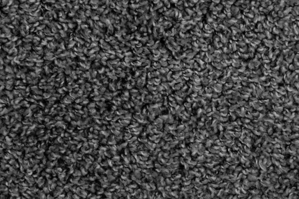 Black natural fleece carpet texture background. Dark wool fabric texture. fragment gray shaggy mat