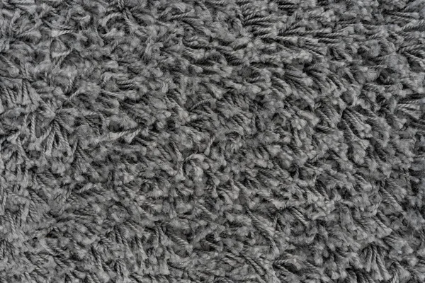 Black natural fleece carpet texture background. Dark wool fabric texture. fragment gray shaggy mat