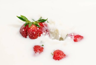 Kırmızı doğal olgun çilekler süt kremasına dökülüyor.