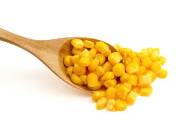Beyaz arka planda izole edilmiş tahta kaşıkta doğal mısır tohumları.