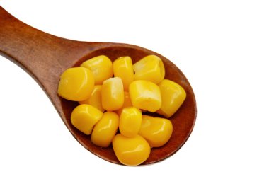 Beyaz arka planda izole edilmiş tahta kaşıkta doğal mısır tohumları.