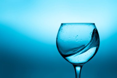 Mavi zemin üzerinde sıvı (beyaz şarap) olan şarap kadehi