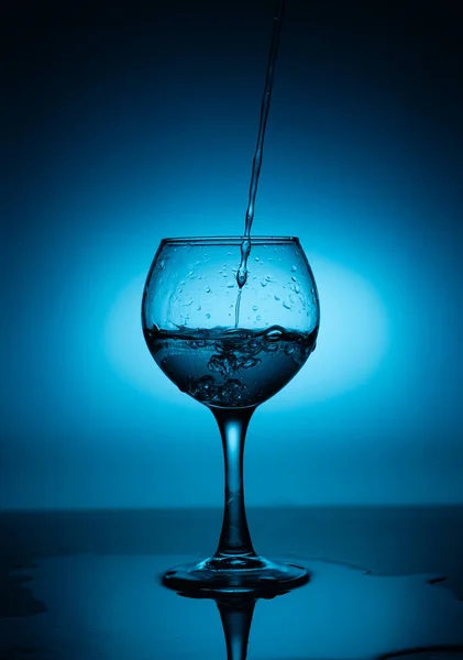 Wijnglas Met Vloeiende Witte Wijn Water Een Blauwe Hellingsondergrond — Stockfoto