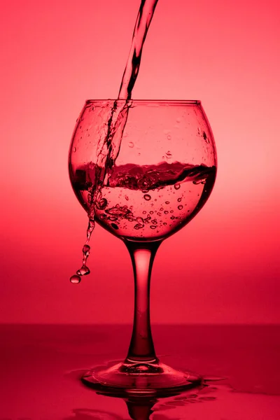Fließende Flüssigkeit Wein Einem Glas Auf Rotem Hintergrund — Stockfoto