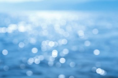 Hassas mavi desenli Bokeh deniz arka planı. Güneşli bir günde, suyun üzerinde bulanık mavi Bokeh parıltısı. dinlenme ve seyahat