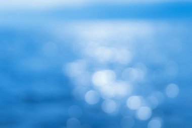Hassas mavi desenli Bokeh deniz arka planı. Güneşli bir günde, suyun üzerinde bulanık mavi Bokeh parıltısı. dinlenme ve seyahat