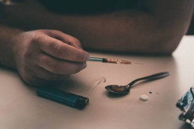 Şırınga eroin metamfetamin bağımlılığıyla masada duran bir bağımlı.
