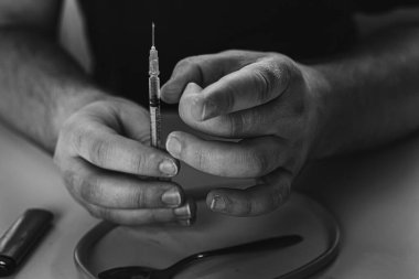 Şırınga eroin metamfetamin bağımlılığıyla masada duran bir bağımlı.