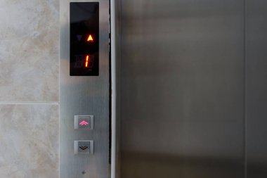 Metalik asansör paneli, düğmeli ve ekranlı. Asansördeki metal düğmelerin içerisi ve yakınlığı