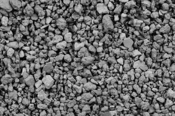 Gray small rocks ground texture. black small road stone background. gravel pebbles stone seamless texture. dark background of crushed granite gravel, close up. clumping clay