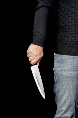 Adamın eli siyah arka planda bir bıçak tutuyor. Şiddet ve cinayet konuları. Hırsız, katil, tecavüzcü, manyak