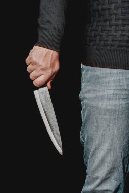 Adamın eli siyah arka planda bir bıçak tutuyor. Şiddet ve cinayet konuları. Hırsız, katil, tecavüzcü, manyak