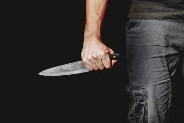 Adamın eli siyah arka planda bir bıçak tutuyor. Şiddet ve cinayet konuları. Hırsız, katil, tecavüzcü, manyak