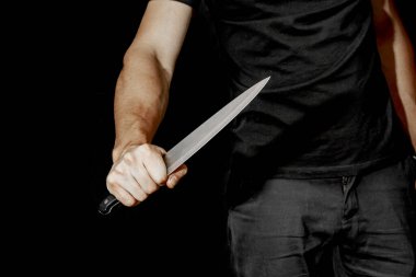 Adamın eli siyah arka planda bir bıçak tutuyor. Şiddet ve cinayet konuları. Hırsız, katil, tecavüzcü, manyak