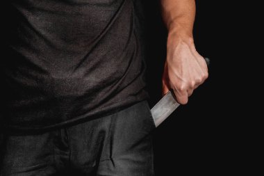 Adamın eli siyah arka planda bir bıçak tutuyor. Şiddet ve cinayet konuları. Hırsız, katil, tecavüzcü, manyak