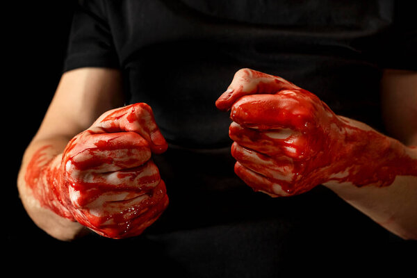 Male hands showing various gestures in the blood on a black background. broken fists in the blood