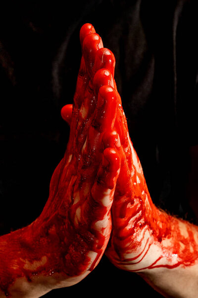 Мужские руки, показывающие различные жесты в крови на черном фоне. Руки с жестом молитвы и сложенными пальмами