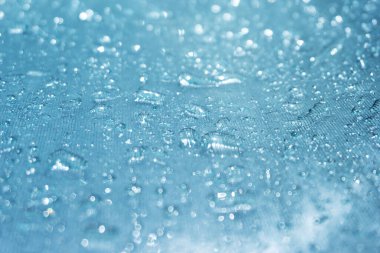 Mavi cam arka planda yağmur damlaları, cam yüzeyde parlak yağmur damlaları, yüzme havuzunda su damlaları.