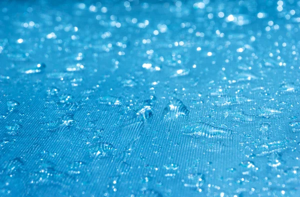 雨滴落在蓝色的玻璃杯底座上 晶莹的雨滴落在玻璃杯表面 水滴落在游泳池的近处 — 图库照片