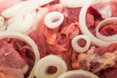 Taze çiğ et parçaları soğan halkaları dokusu arka plan, kırmızı sulu et parçaları yakın plan, bir kukla önünde et