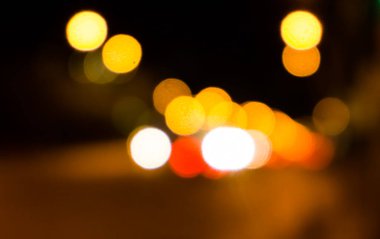 Bokeh şehrin dokusunun gece sokaklarını aydınlatıyor. Retro tonlu bulanık ışıklar, kentsel soyut arkaplan.