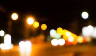 Bokeh şehrin dokusunun gece sokaklarını aydınlatıyor. Retro tonlu bulanık ışıklar, kentsel soyut arkaplan.