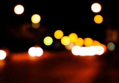 Bokeh şehrin dokusunun gece sokaklarını aydınlatıyor. Retro tonlu bulanık ışıklar, kentsel soyut arkaplan.