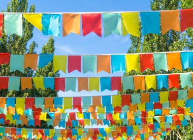 Mavi gökyüzüne ve ağaçlara karşı çok renkli bayraklar üçgen şeklinde. Şehir sokak tatili teması için iyi bir geçmiş.