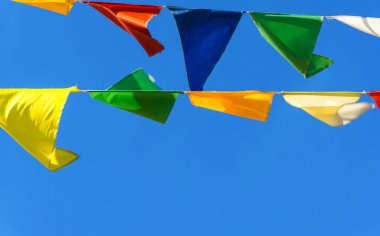 Çok renkli bayraklar mavi gökyüzüne karşı üçgen şeklinde şekillenir. Şehir sokak tatili teması için iyi bir geçmiş.