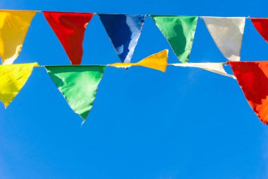 Çok renkli bayraklar mavi gökyüzüne karşı üçgen şeklinde şekillenir. Şehir sokak tatili teması için iyi bir geçmiş.