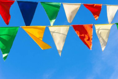 Çok renkli bayraklar mavi gökyüzüne karşı üçgen şeklinde şekillenir. Şehir sokak tatili teması için iyi bir geçmiş.