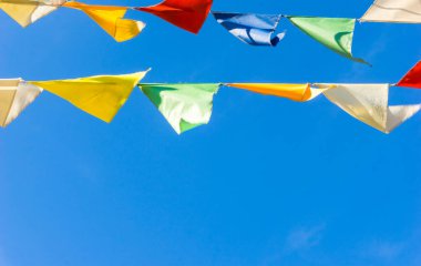 Çok renkli bayraklar mavi gökyüzüne karşı üçgen şeklinde şekillenir. Şehir sokak tatili teması için iyi bir geçmiş.