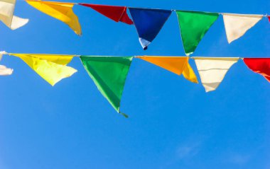 Çok renkli bayraklar mavi gökyüzüne karşı üçgen şeklinde şekillenir. Şehir sokak tatili teması için iyi bir geçmiş.