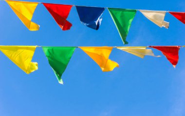 Çok renkli bayraklar mavi gökyüzüne karşı üçgen şeklinde şekillenir. Şehir sokak tatili teması için iyi bir geçmiş.