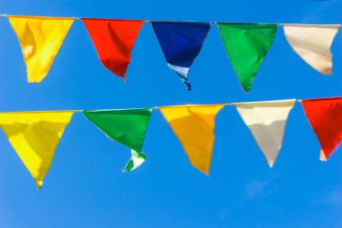 Çok renkli bayraklar mavi gökyüzüne karşı üçgen şeklinde şekillenir. Şehir sokak tatili teması için iyi bir geçmiş.