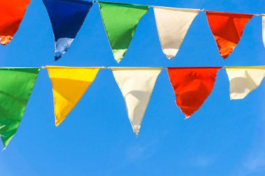 Çok renkli bayraklar mavi gökyüzüne karşı üçgen şeklinde şekillenir. Şehir sokak tatili teması için iyi bir geçmiş.