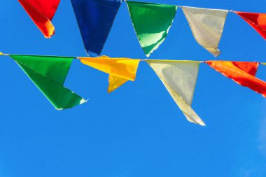 Çok renkli bayraklar mavi gökyüzüne karşı üçgen şeklinde şekillenir. Şehir sokak tatili teması için iyi bir geçmiş.
