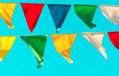 Çok renkli bayraklar mavi gökyüzüne karşı üçgen şeklinde şekillenir. Şehir sokak tatili teması için iyi bir geçmiş.