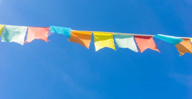 Çok renkli bayraklar mavi gökyüzüne karşı üçgen şeklinde şekillenir. Şehir sokak tatili teması için iyi bir geçmiş.