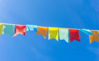 Çok renkli bayraklar mavi gökyüzüne karşı üçgen şeklinde şekillenir. Şehir sokak tatili teması için iyi bir geçmiş.
