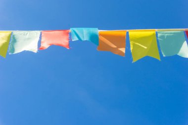 Çok renkli bayraklar mavi gökyüzüne karşı üçgen şeklinde şekillenir. Şehir sokak tatili teması için iyi bir geçmiş.