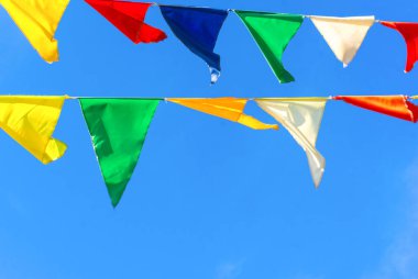 Çok renkli bayraklar mavi gökyüzüne karşı üçgen şeklinde şekillenir. Şehir sokak tatili teması için iyi bir geçmiş.