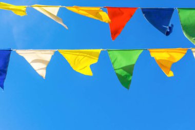 Çok renkli bayraklar mavi gökyüzüne karşı üçgen şeklinde şekillenir. Şehir sokak tatili teması için iyi bir geçmiş.