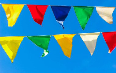 Çok renkli bayraklar mavi gökyüzüne karşı üçgen şeklinde şekillenir. Şehir sokak tatili teması için iyi bir geçmiş.